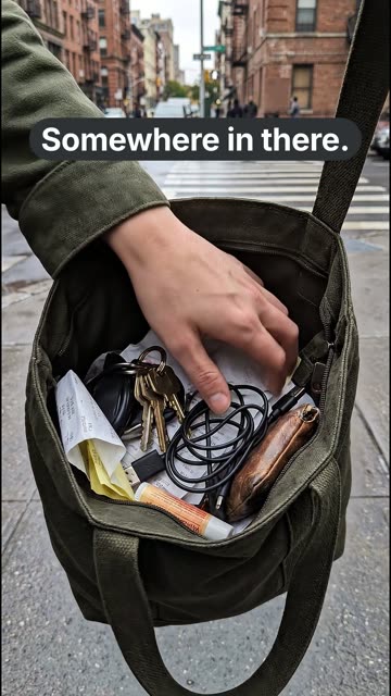 A vertical ad: a hand rummaging blindly through a crowded tote bag on a city sidewalk, with the words “Somewhere in there.”
